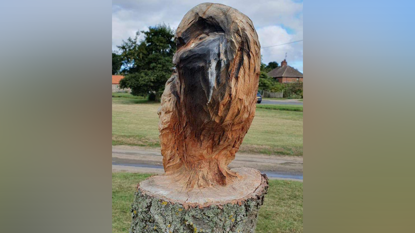 A wooden owl sculpture made from a cherry tree which has been sprayed with black paint.