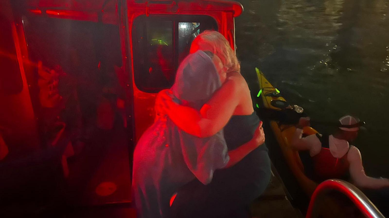 Two women hugging in the dark on a boat