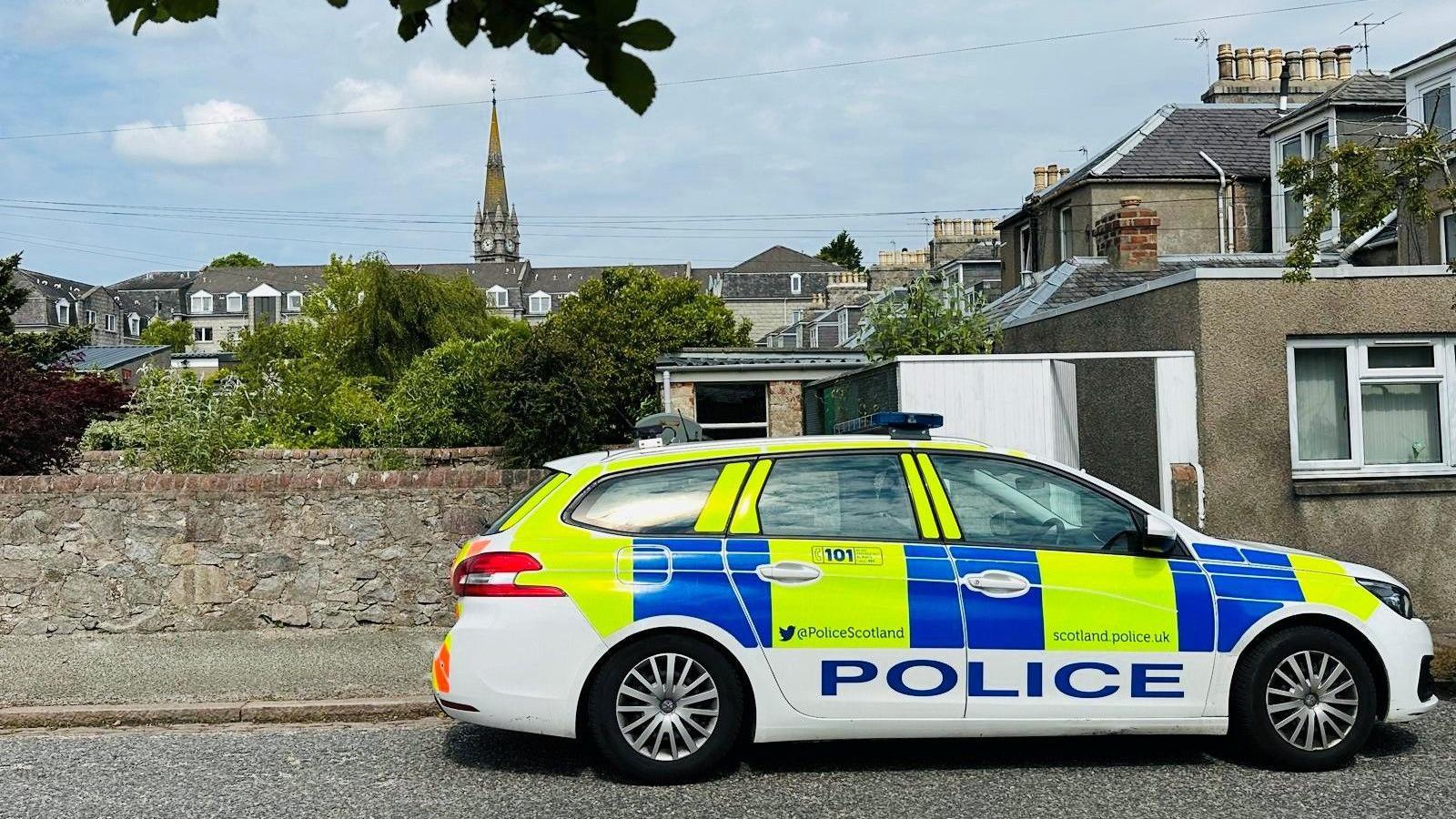 Police car in Aberdeen at scene of a drug operation in Aberdeen, a church spire is in the background.