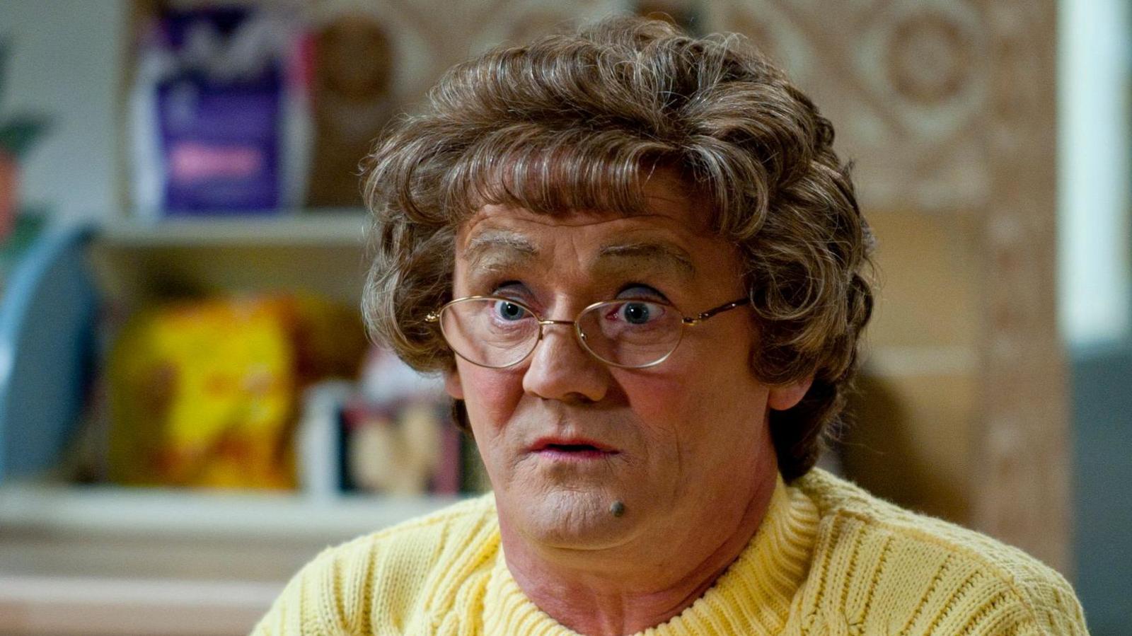 Brendan O'Carroll as Agnes Brown, wearing a yellow cardigan on the show's kitchen set