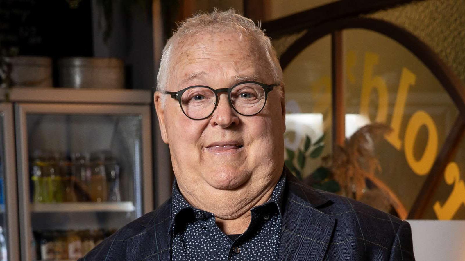 Ian Smith wearing black glasses, a navy and white spotted shirt and a navy checked jacket