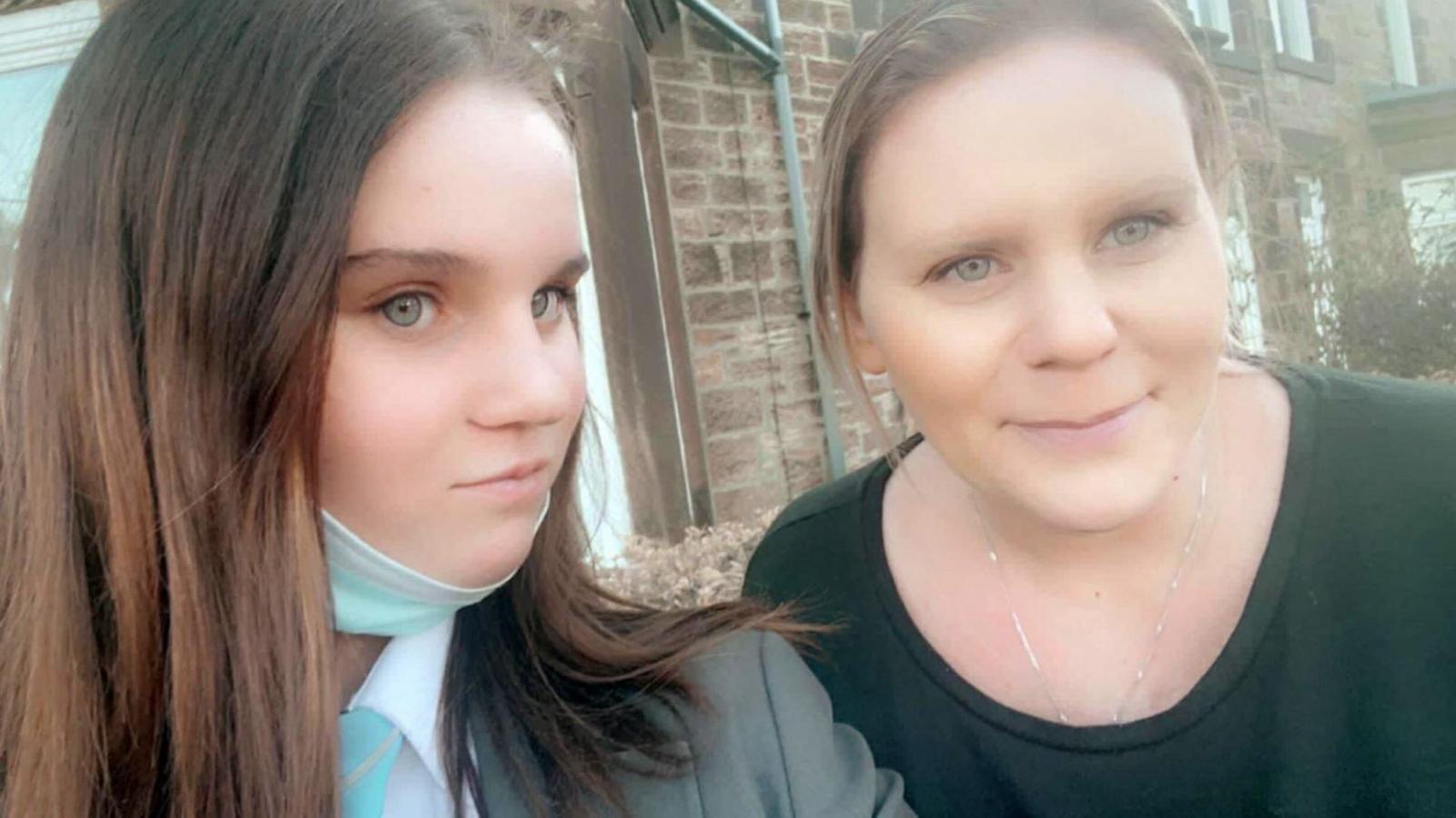 Holly takes a selfie with her mother. Holly has long brown hair and Micala has blond hair, both are looking at the camera smiling.