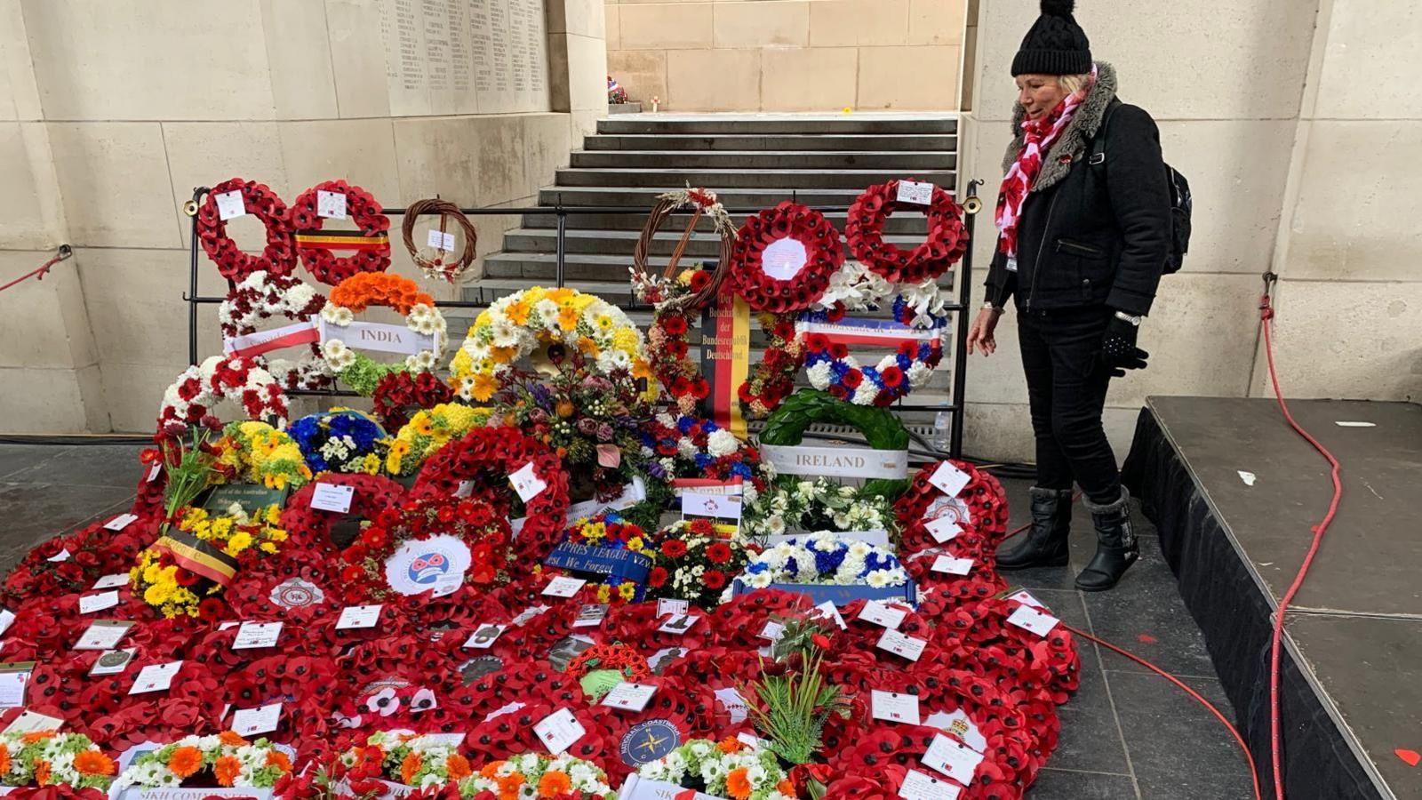 Sadie Nine, standing next to a large amount of wreaths, made from poppies, placed on the ground