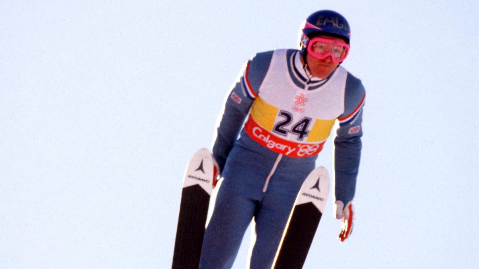 Eddie "The Eagle" Edwards in mid air as he competes in ski jumping at the 1988 Winter Olympics in Calgary. He is wearing a light blue sky suit, goggles and a blue crash helmet