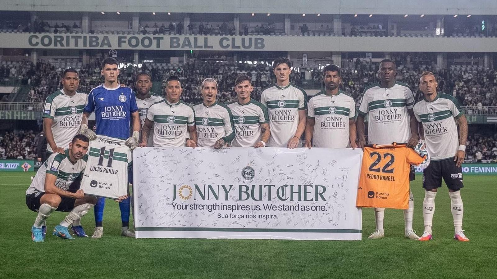 Coritiba players hold a sign that reads: "Jonny Butcher, your strength inspires us. We stand as one"