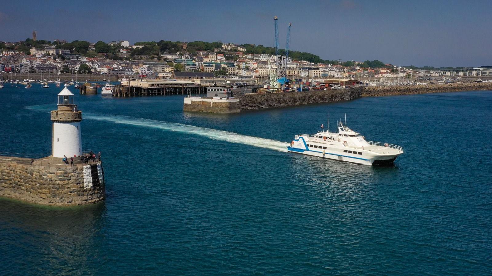 A passenger ferry leaving St Peter Port Harbour. You can see St Peter Port sea front in the background.