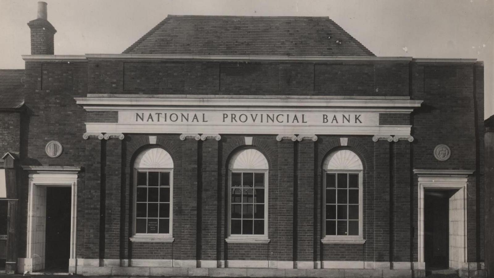 Black and white photo from 1960 shows the Georgian style National Provincial Bank, a sign says that above the three arched windows and imposing doorways at each end of the building.