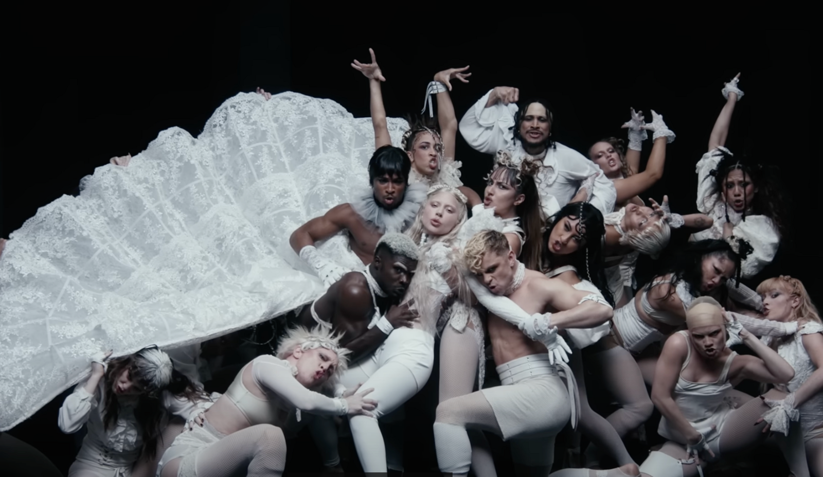 A still from Lady Gaga's Abracadbra video, showing the star with dozens of dancers in a baroque pose