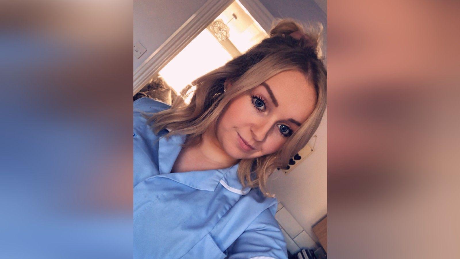 Jessica Thorpe in her nurse uniform, slightly smiling at the camera while taking a selfie.