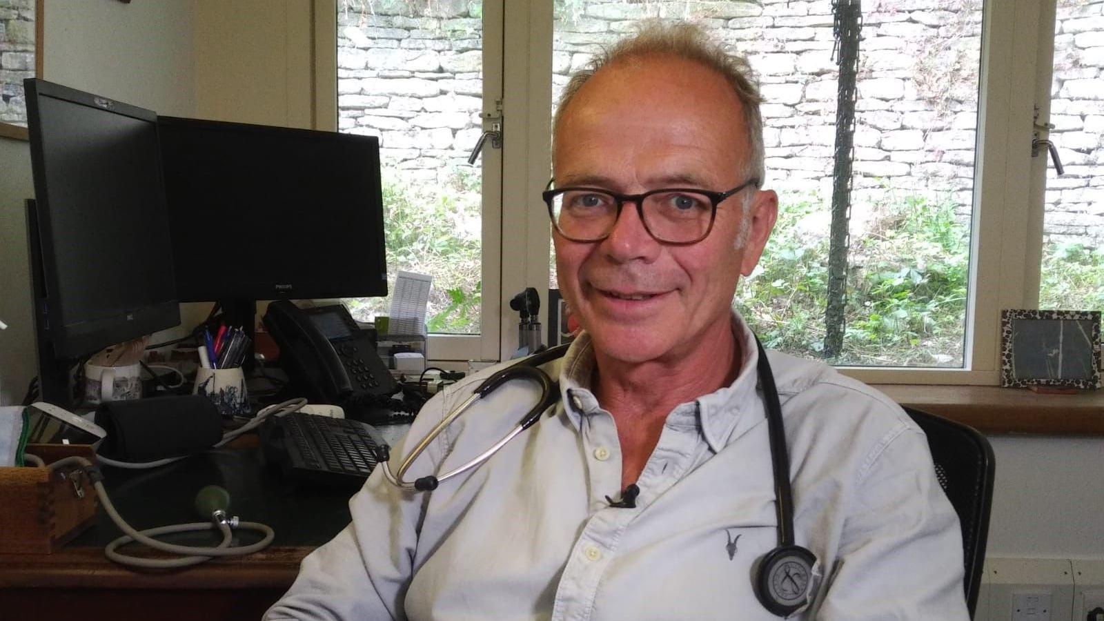 A man with white hair and a stethoscope around his neck