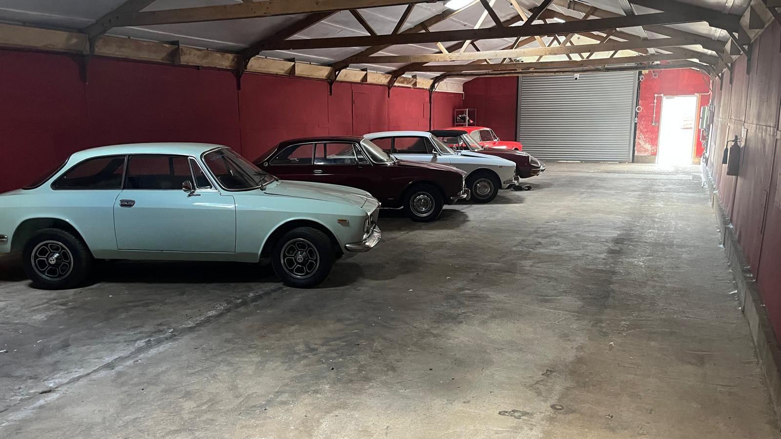 Five vintage cars parked side by side in a storage unit