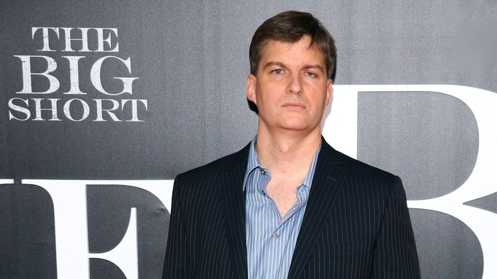 A man dressed in a pinstripe suit and shirt stands in front a banner advertising a film titled The Big Short