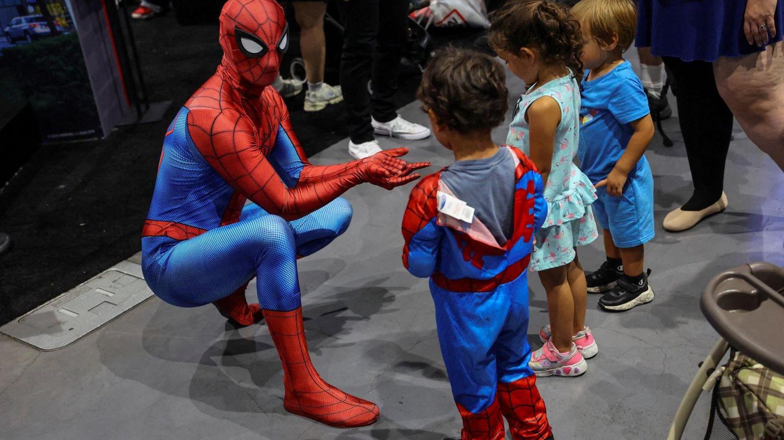 man in spiderman costume speaking to children