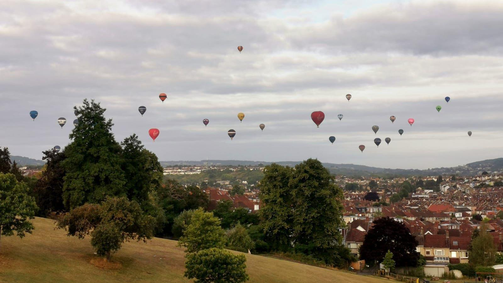 Balloons pictured flying in the sky in Bristol taken from a steep park