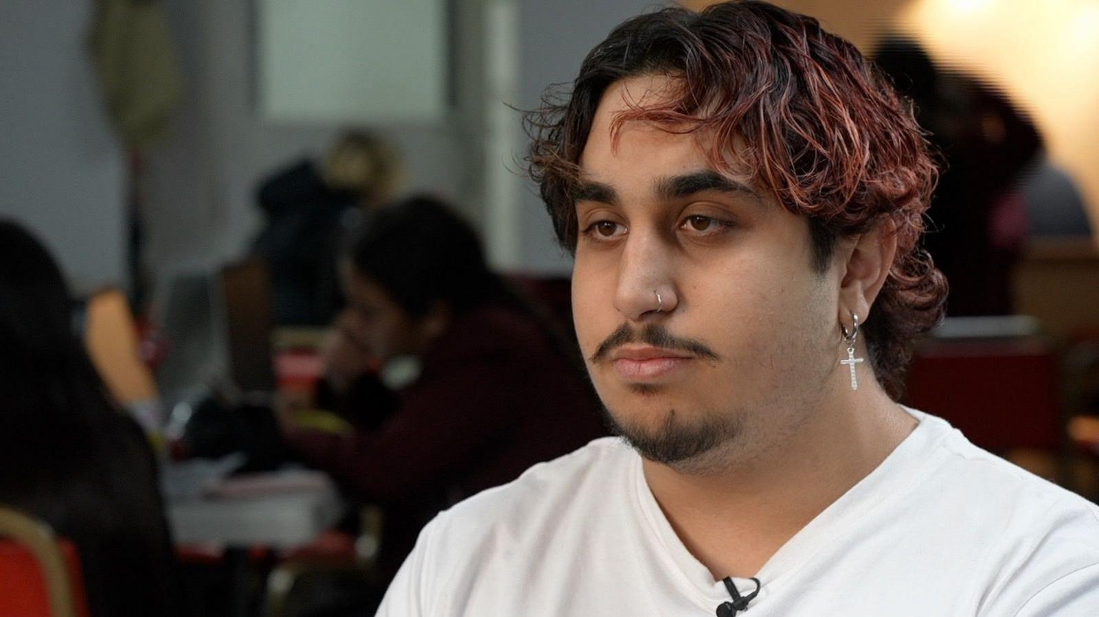 Dalibor Ferenc has pink tinted hair and is sitting with a neutral expression on his face and wearing a white t-shirt. 