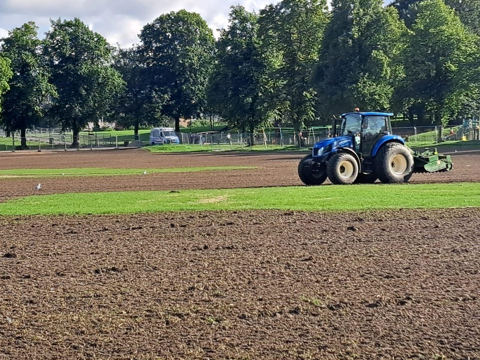 A tractor driving over a muddy area of grassland