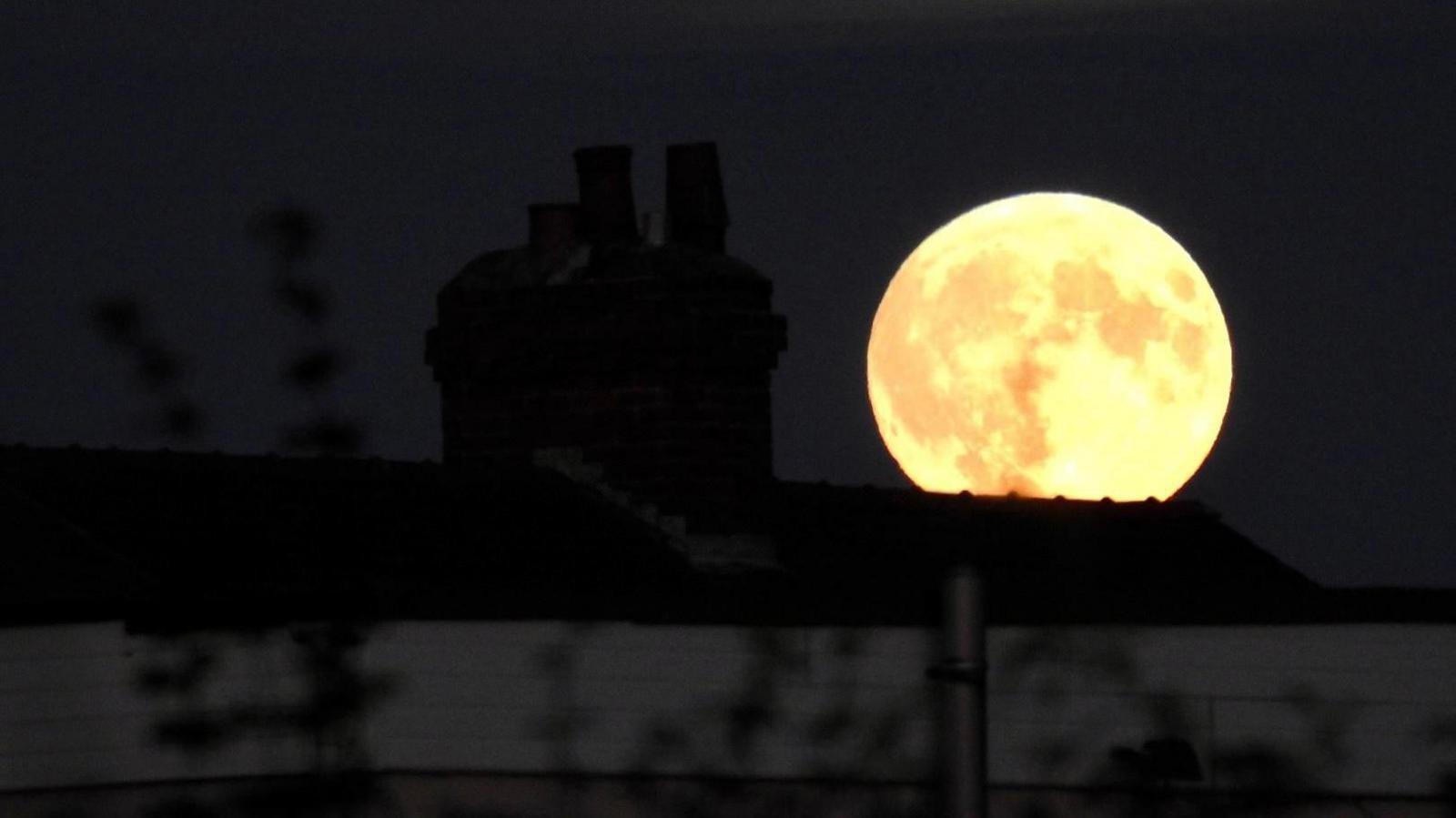 A yellow moon glows above the dark shadow of a house in Wakefield.