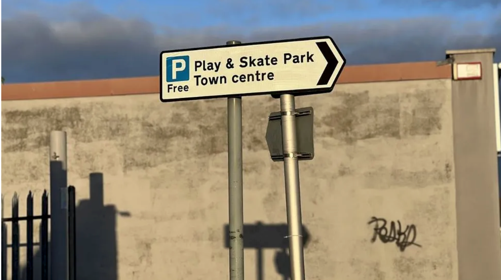 A car park sign pointing towards a skate park