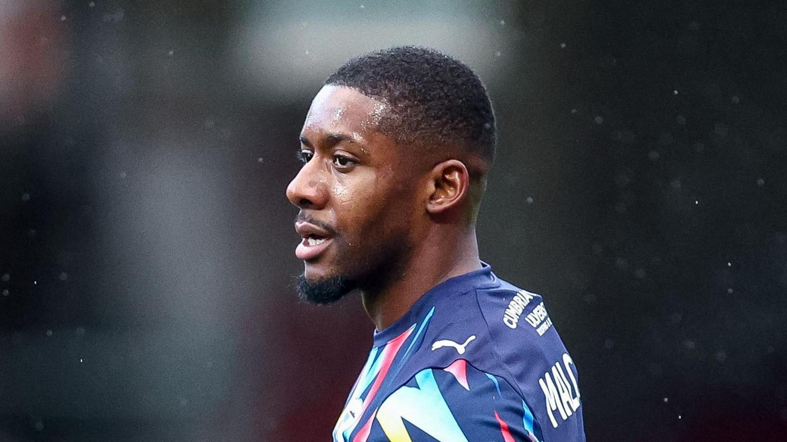 Jovan Malcolm in a Barrow away kit with his head turned to the left