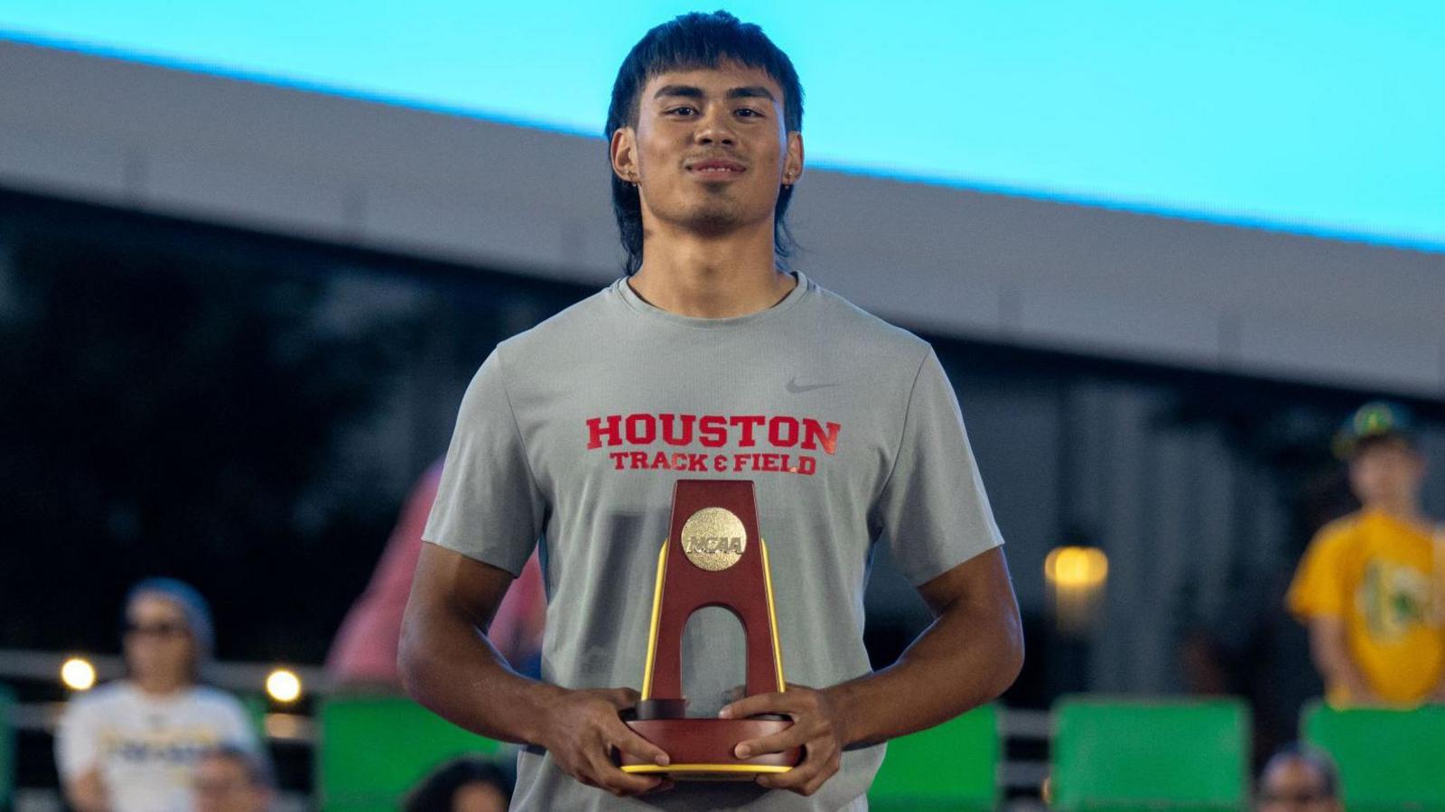 Louie Hinchliffe is presented with his trophy following his 100m victory at the NCAA Championships