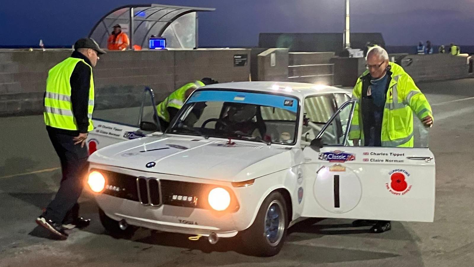 Three men working on a white BMW 2002ti