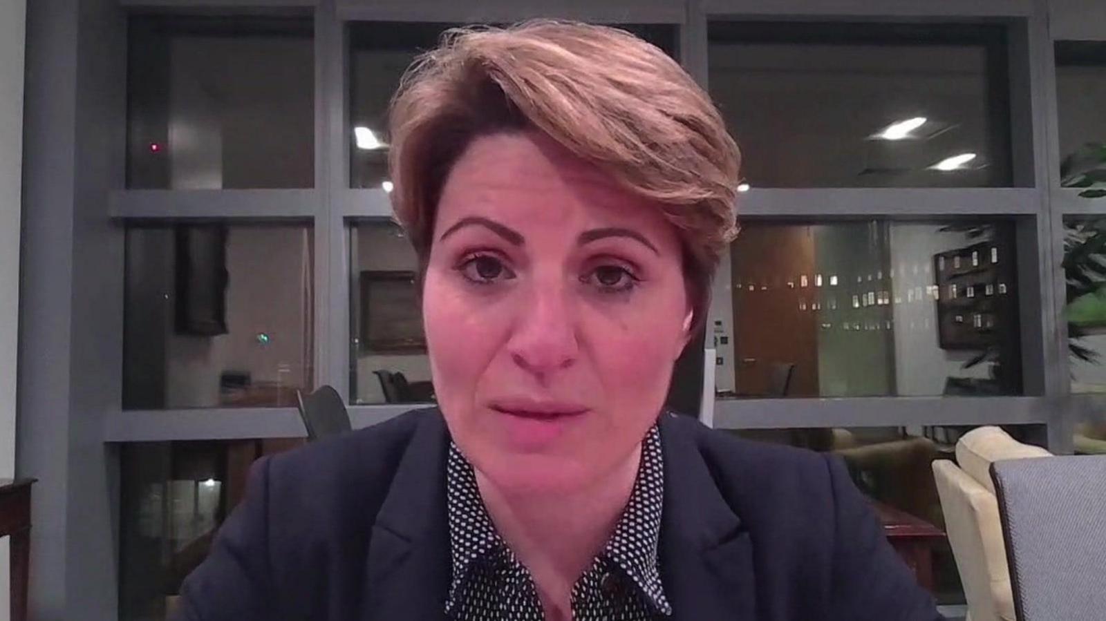 Emma Hardy being interviewed via Zoom. She is wearing a dark speckled top and a dark jacket and sitting in a room with a plant and a large window behind her.