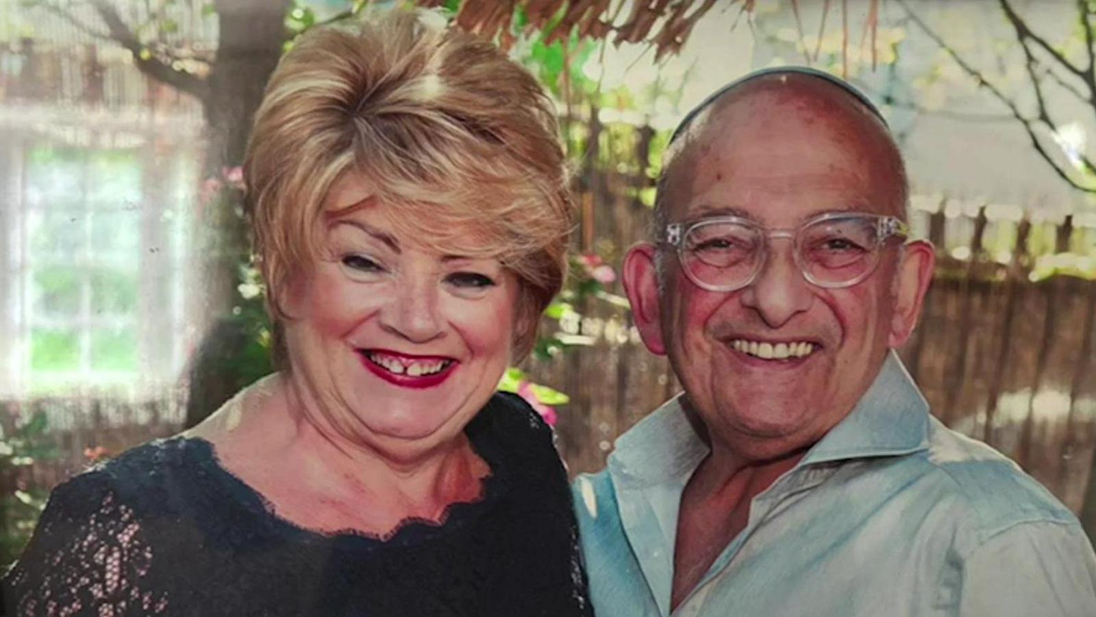 Elaine Marco, who has short blonde hair, and Philip Marco, who is bald and is wearing a Jewish Kippah and glasses, smile at the camera