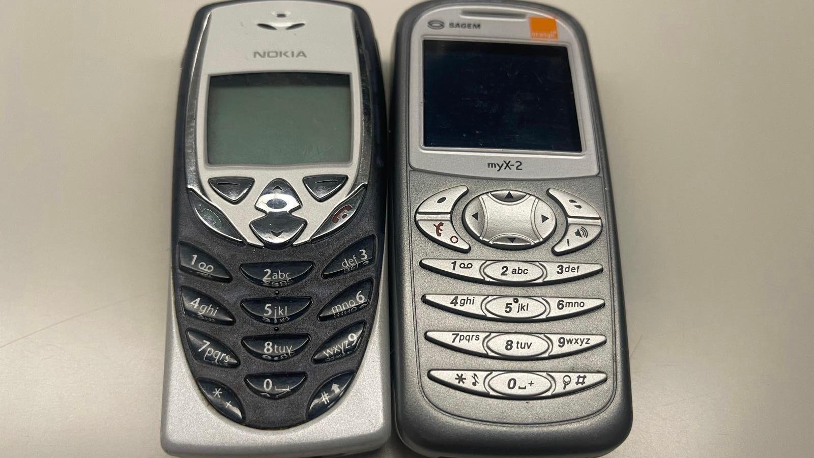 Two brick phones next to each other, one is a black and silver Nokia the other is a grey silver Sagem myX-2.