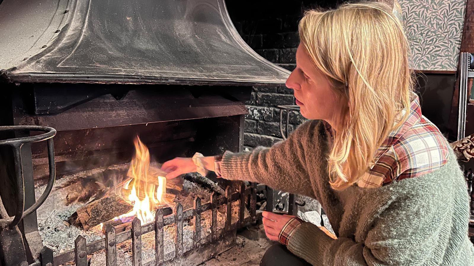 Laura Walsha, kitchen porter at the venue, lighting a fire