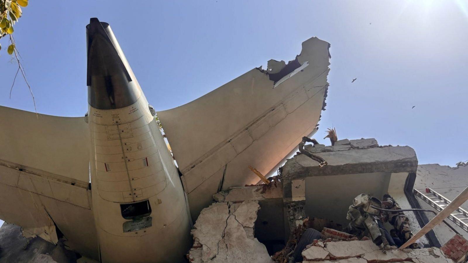 Part of the wreckage of the plane sits on top of a partially destroyed building