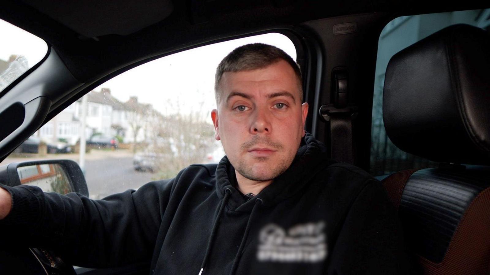 Man sitting in drivers seat of a van.