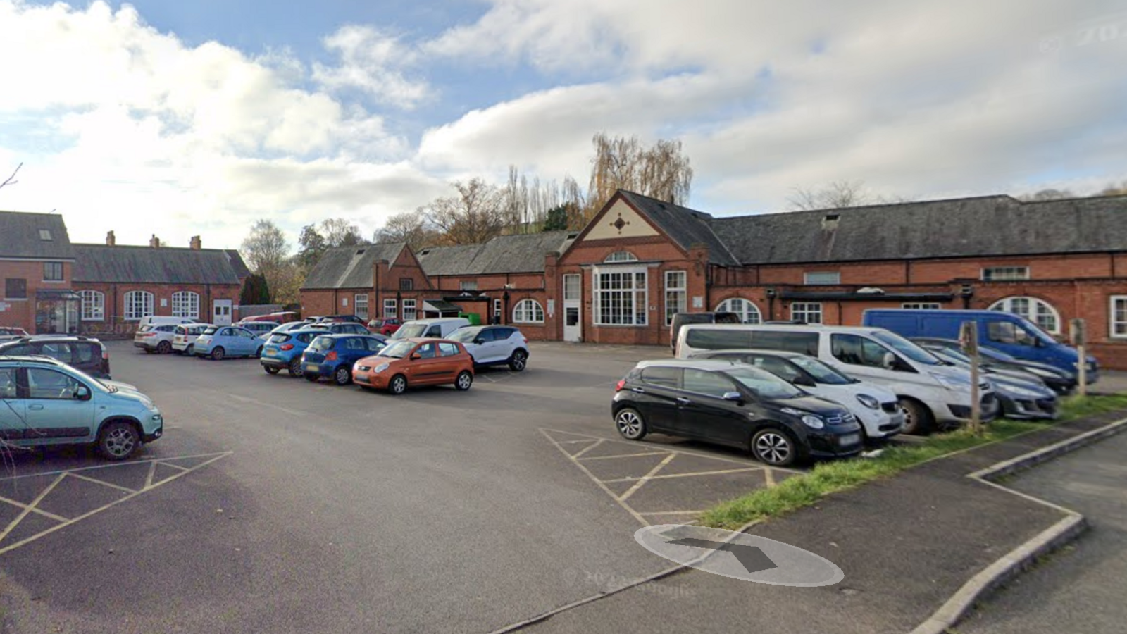 A google street view of Old Heathcoat School Community Centre from the car park. There are cars parked in the car park. 