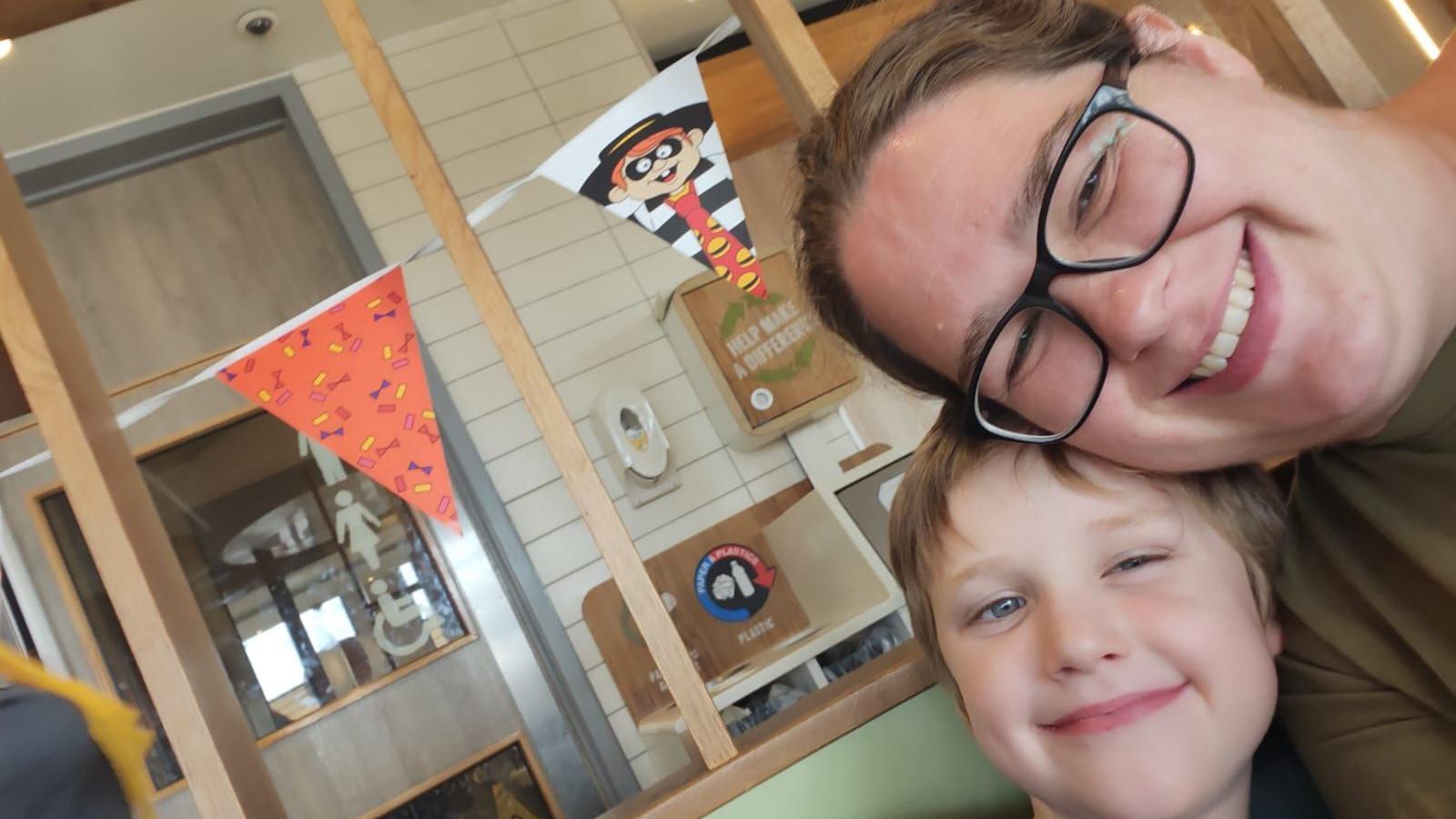 Stephanie takes a selfie with her young son Glen, both of whom are looking into the camera and smiling. Stephanie is wearing glasses, while Glen has short brown hair