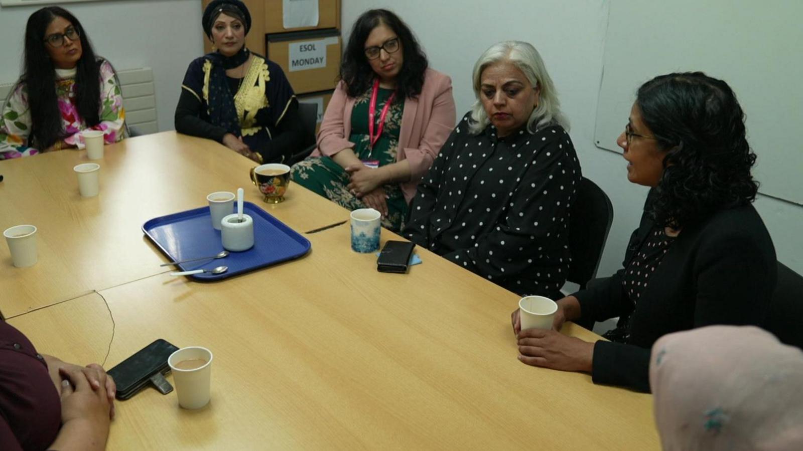 A group of women sitting round a table. They all look to be of South Asian heritage and a mix of ages. They have cups of tea or coffee in front of them.