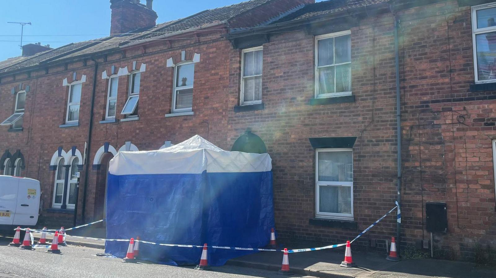 Cordon surrounding a blue and white tent outside a house