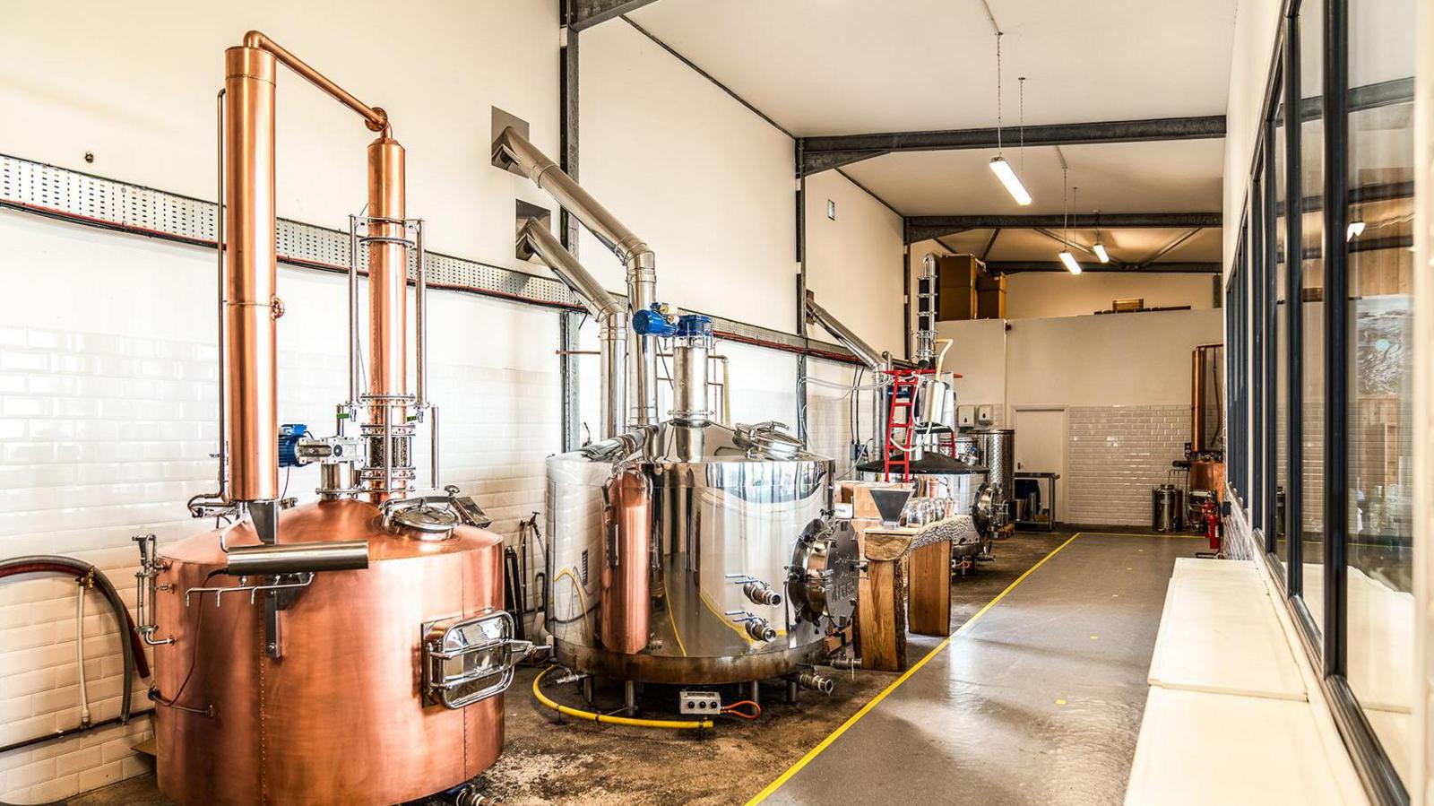 A series of stills in a distillery in different gleaming metals used for the production of gin, whisky and other spirits