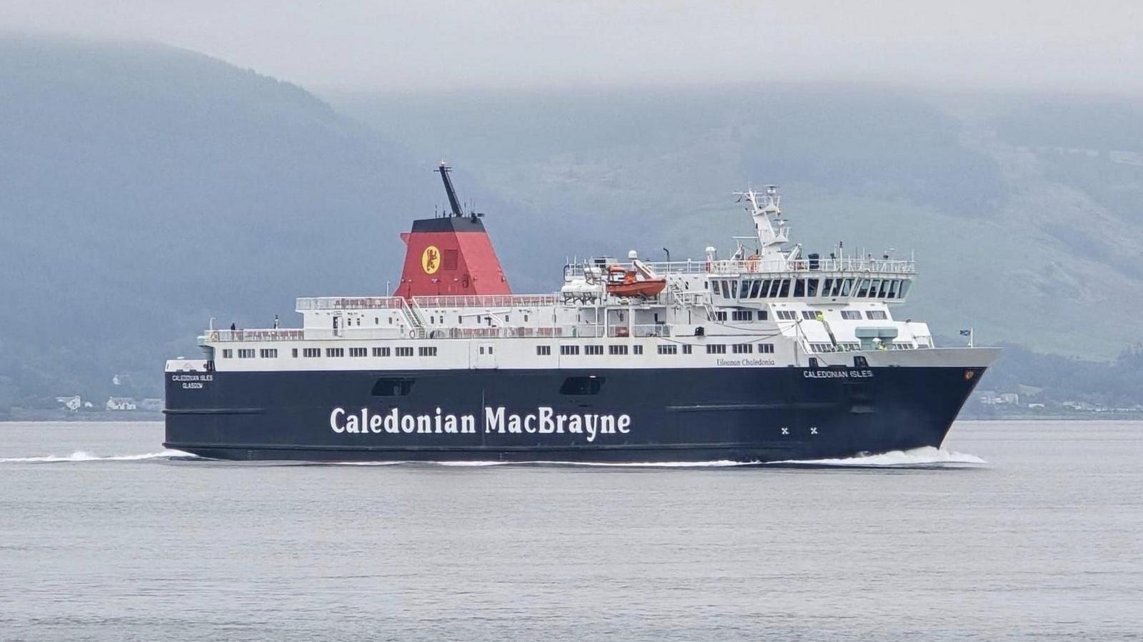 A black and white ship with red funnels and Caledonian Isles written on the bow, sailing on a misty day with hills in the background