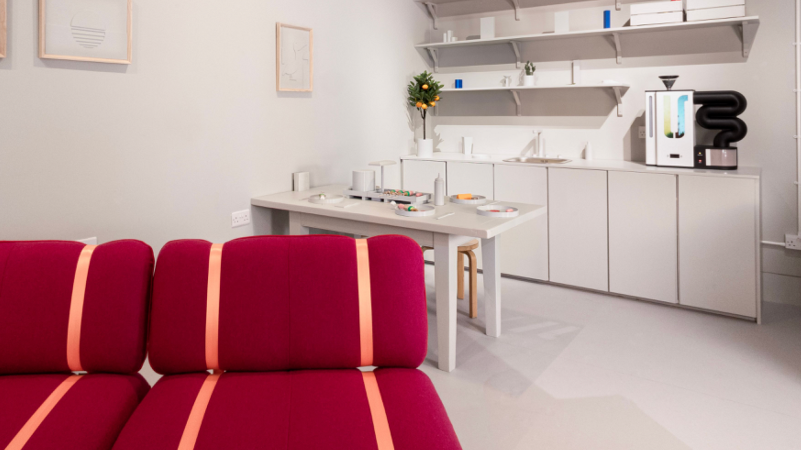 The exhibition's Innovo Room of the Future, a white room with white kitchen units, a white table and a bright red sofa