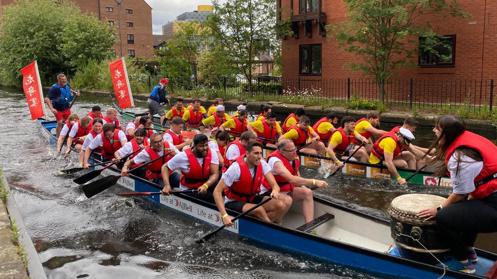 rowers in red life jackets on boats in the canal