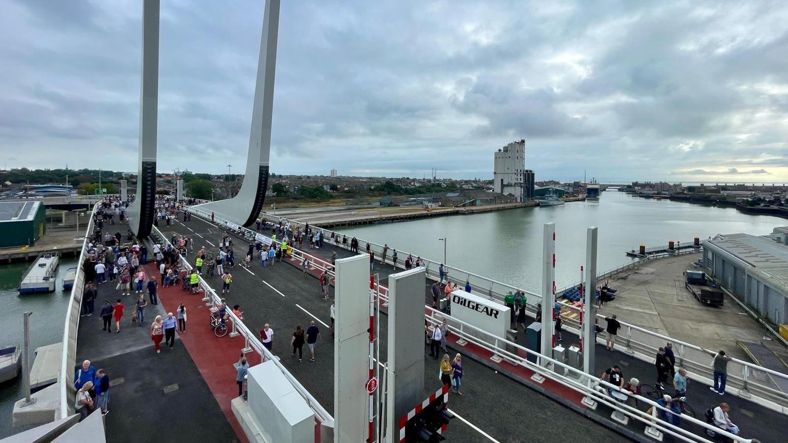 A photo taken from up high of people walking across the bridge. 
