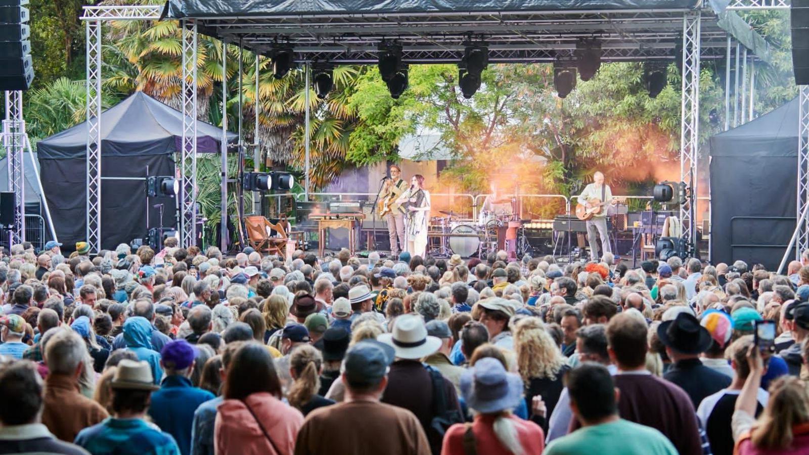 View from the back of the crowd watching PJ Harvey and her band playing on an outdoor stage