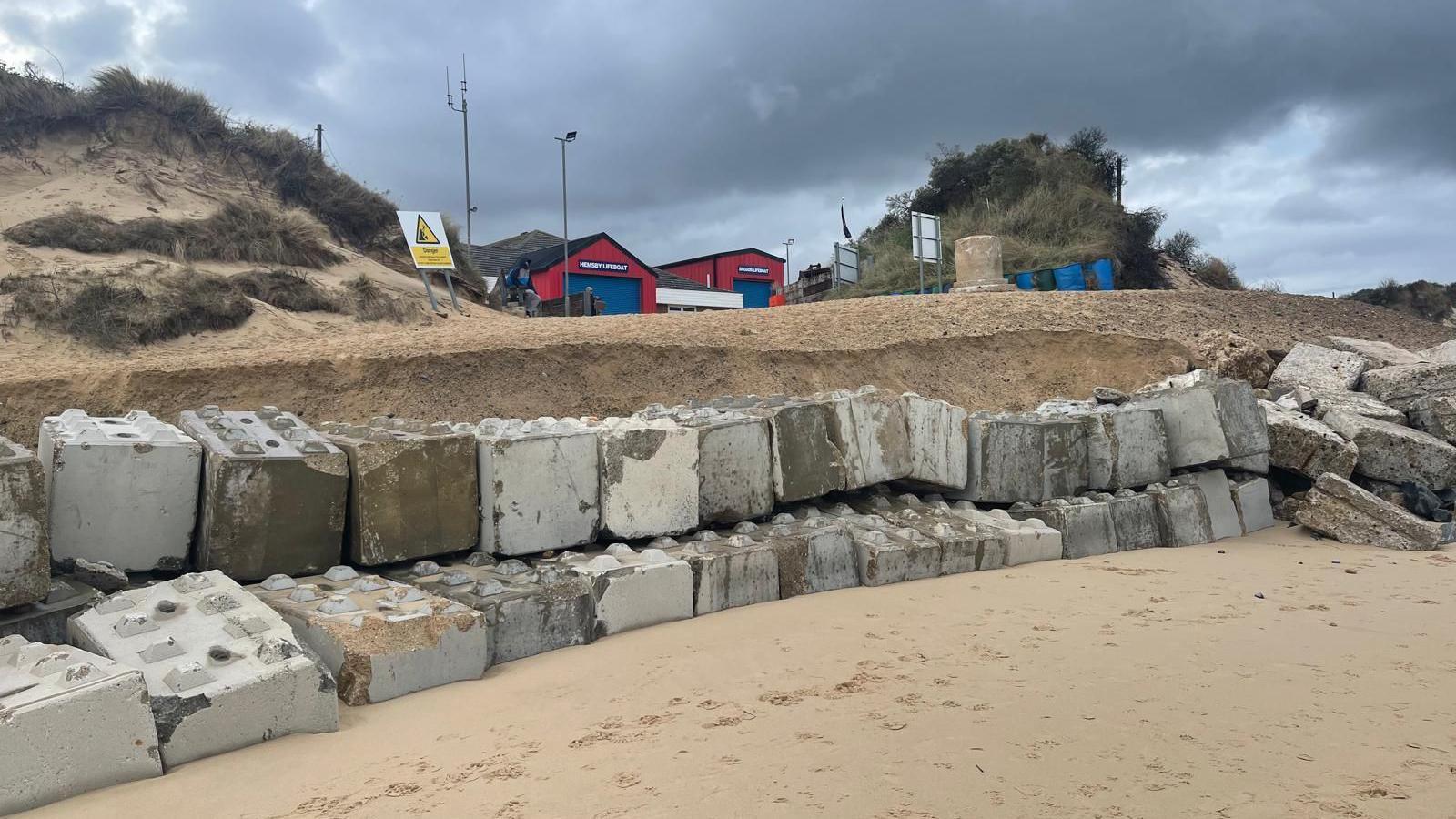 Rock barm is exposed with sandy ridge above and lifeboat station in the distance