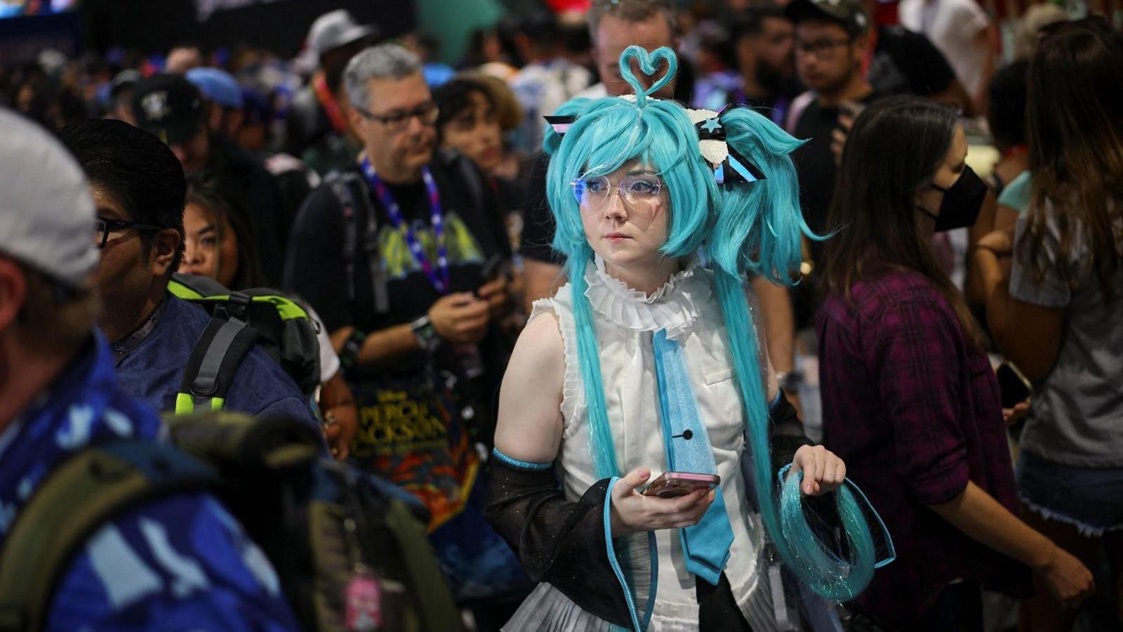 Woman in anime costume with a bright blue wig. holding a phone