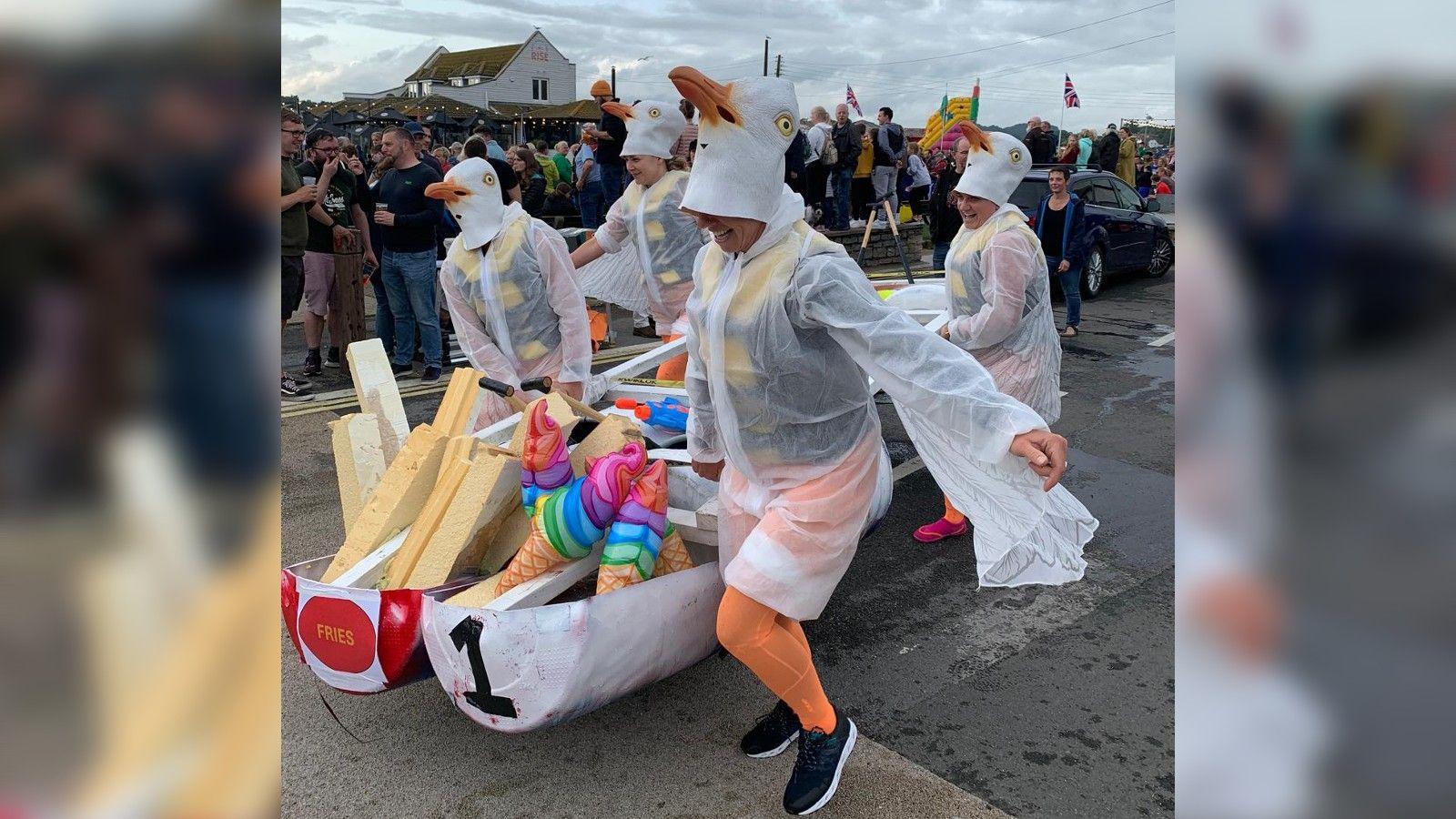 four women dressed as seagulls running with their homemade raft before they enter the water