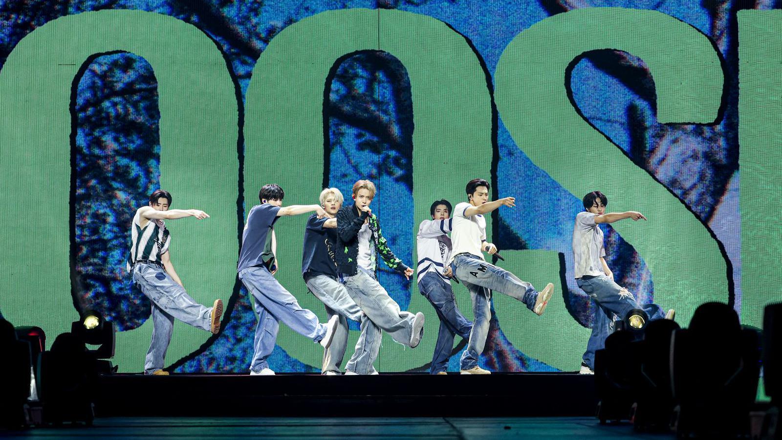 K-pop band ENHYPEN all wearing denim outfits on stage performing.