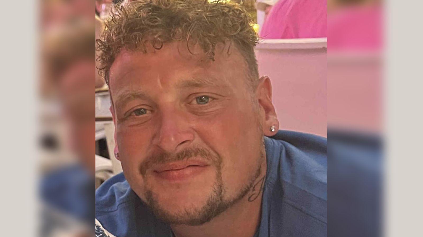 A man with curly red hair and an ear ring.