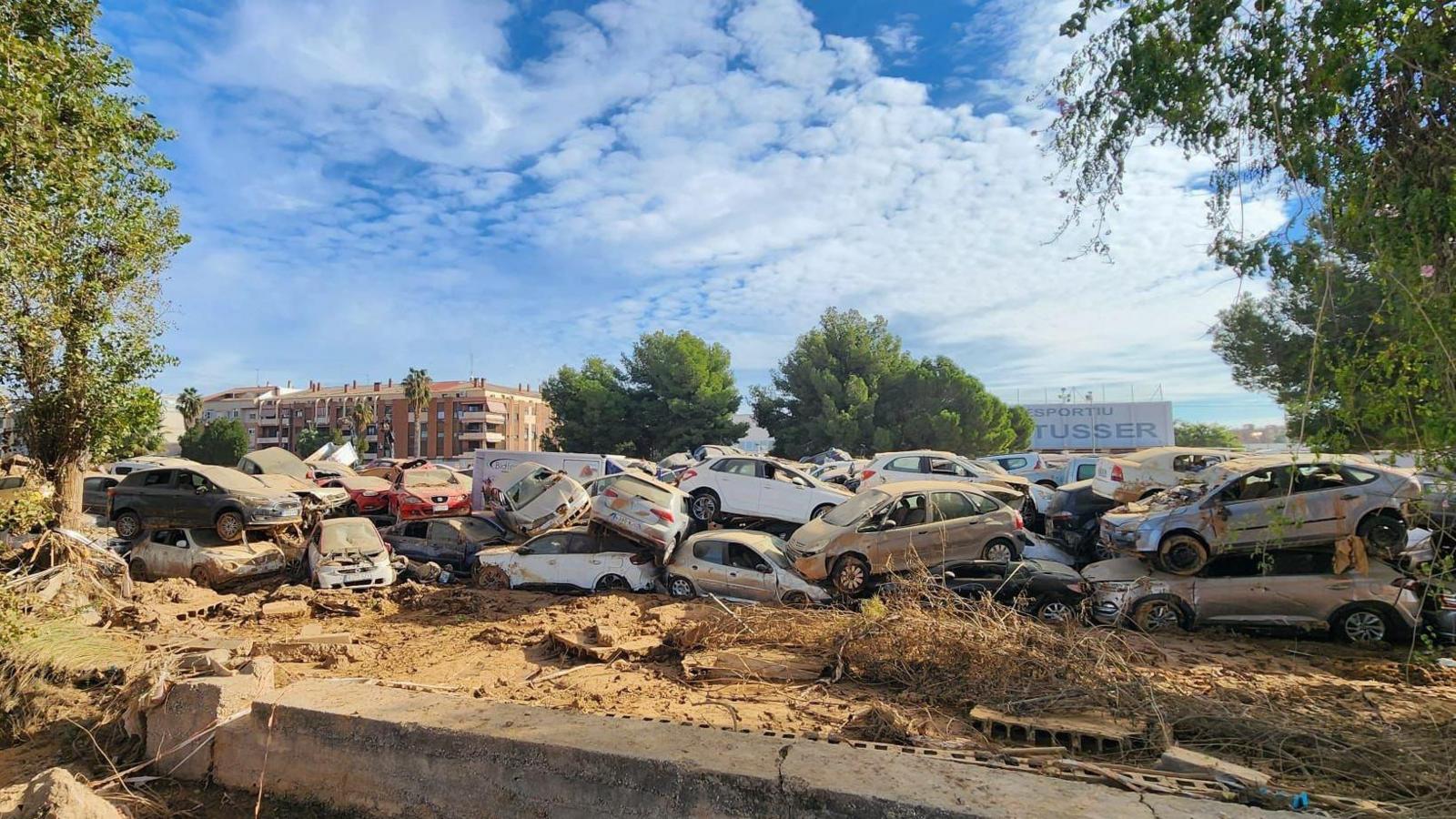 A pile up of around 30 cars which have been left behind in the wake of the flash floods in Valencia. The ground is muddy, the cars have been smashed and are covered in debris, piled around three cars deep.