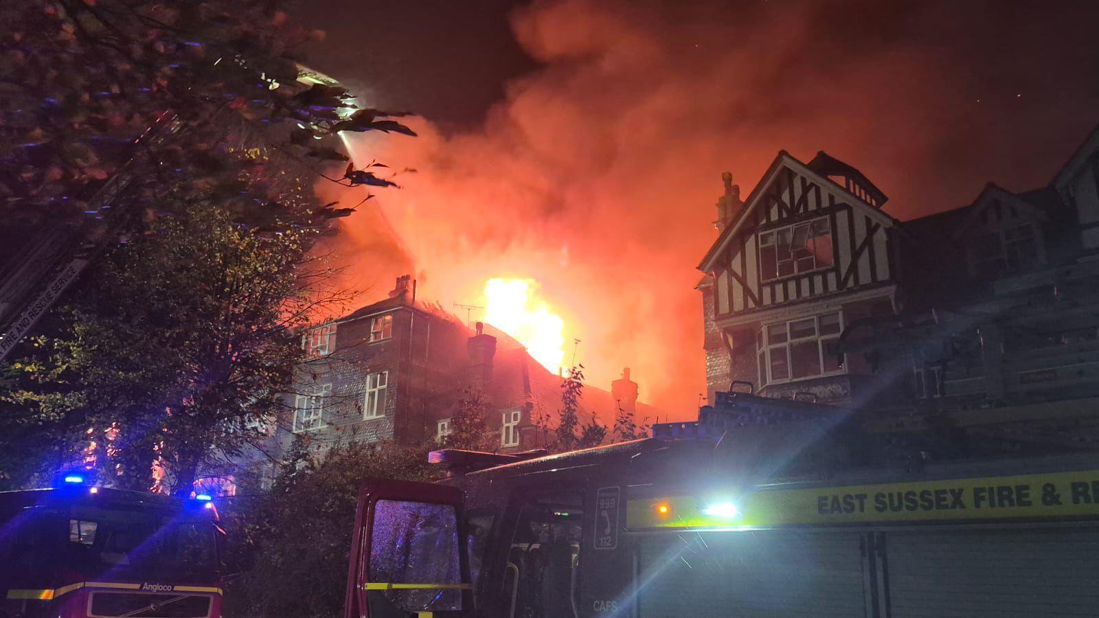 A building on fire. There is a fire engine in the foreground.