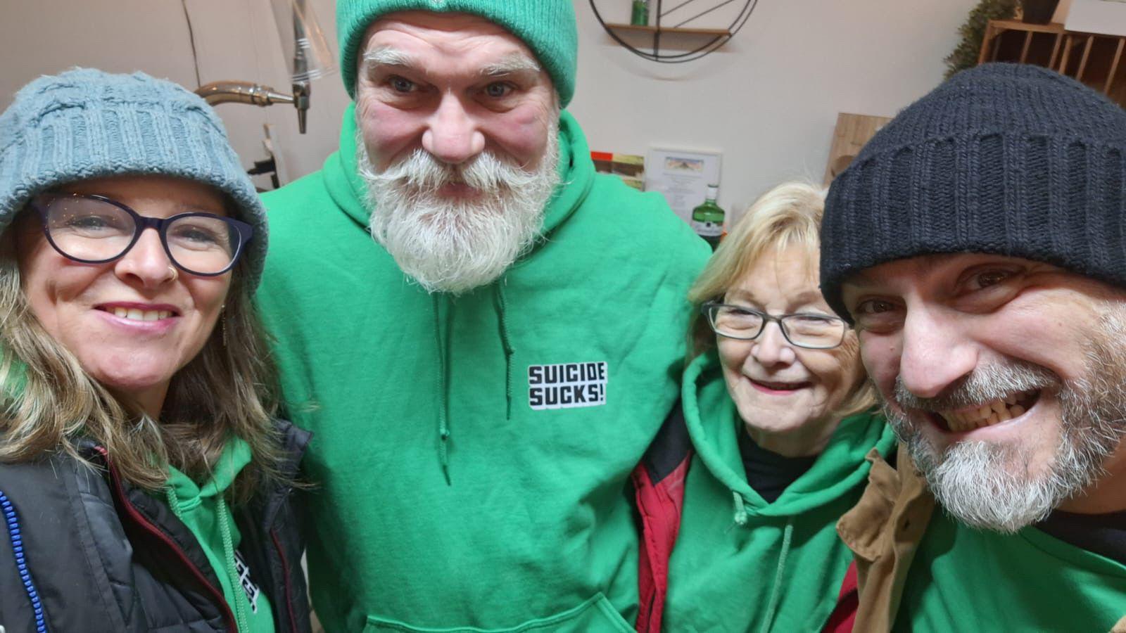 Mick Rowe with volunteers from Suicide Sucks, who are wearing green branded hoodies.