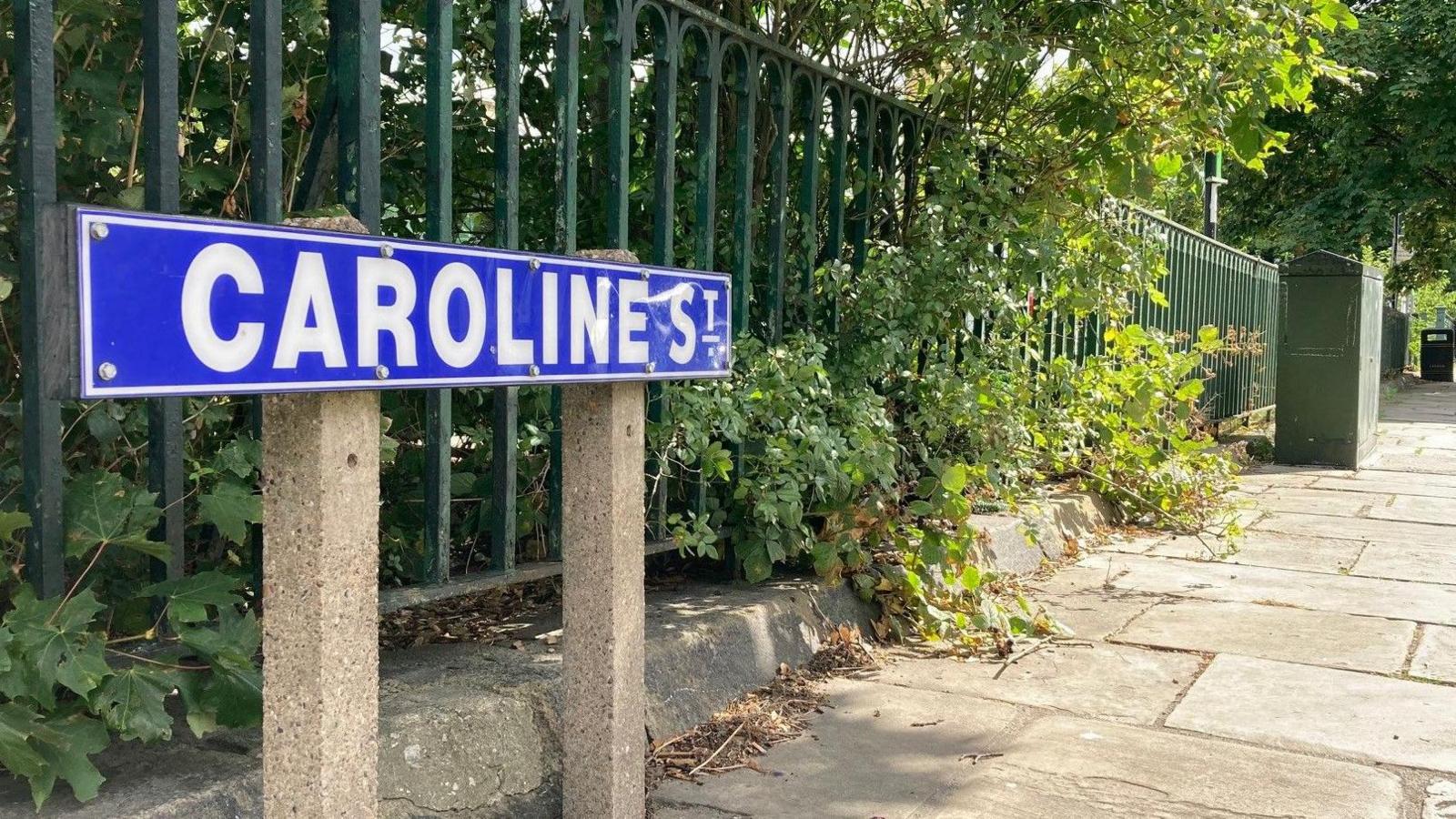 A street sign with white lettering and a blue background spelling out Caroline Street